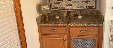 A kitchen with wooden cabinets, a granite countertop, and a fish-themed backsplash.