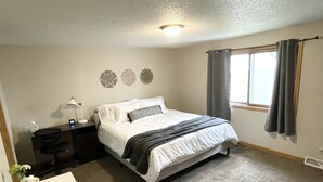 Une chambre à coucher comprenant un lit, une table de chevet, une lampe, des éléments décoratifs sur les murs et une fenêtre avec des rideaux.