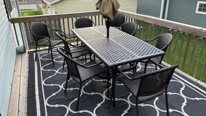 Une terrasse couverte avec une table et des chaises, une pergola et une vue sur les maisons voisines.