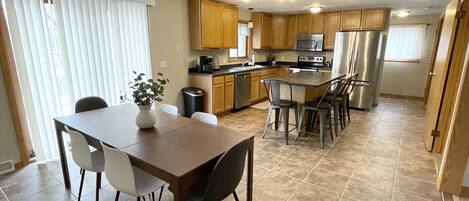 A modern kitchen with wooden cabinets, stainless steel appliances, and a central island with bar stools.
