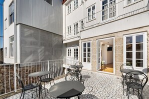 A building with a balcony, outdoor seating, and a stone facade. - LP Heritage 2. 01 w/ City View - Sé Apartamentos (Braga)