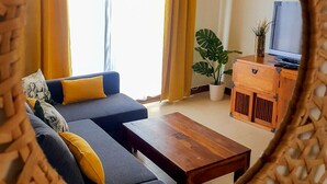 A living room with a sofa, a wooden coffee table, a TV on a wooden cabinet, and a potted plant. - AIOLOS 20 by Buenavilla|Great apartment in the marina of Puerto Calero (Las Palmas)