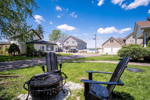 Una calle residencial con casas, una parrilla y dos sillas Adirondack.