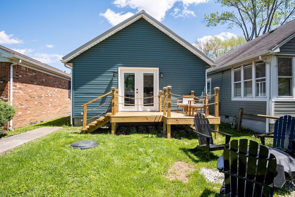 A small, single-story house with a wooden deck and a front door.