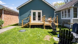 A small, single-story house with a wooden deck and a front door.