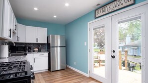 A modern kitchen with white cabinets, a stainless steel refrigerator, and a gas stove.
