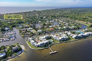 An aerial view of a coastal residential area with a marina, houses, and a large building complex. - Mariner Pointe 323 (Sanibel)