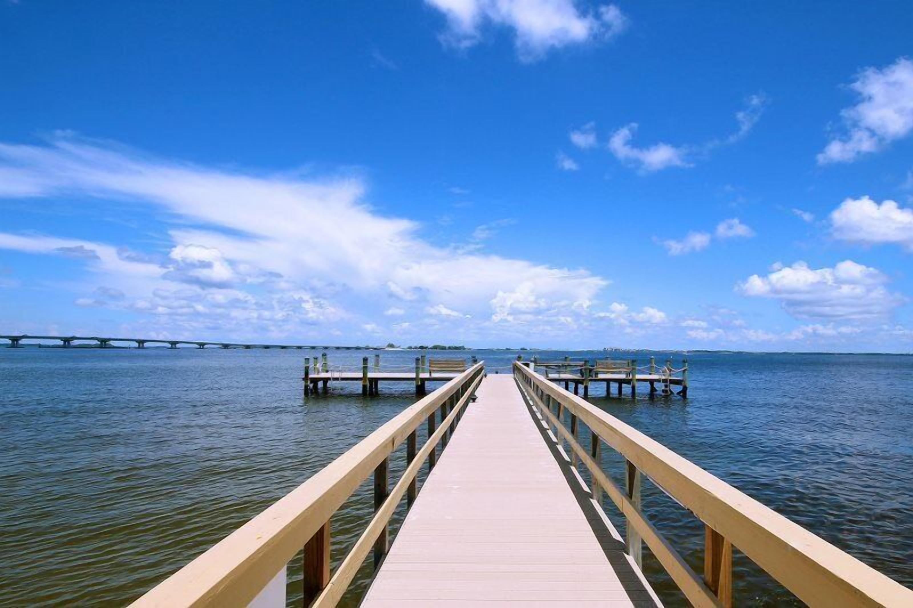 A wooden pier extending into calm water with a clear sky above.