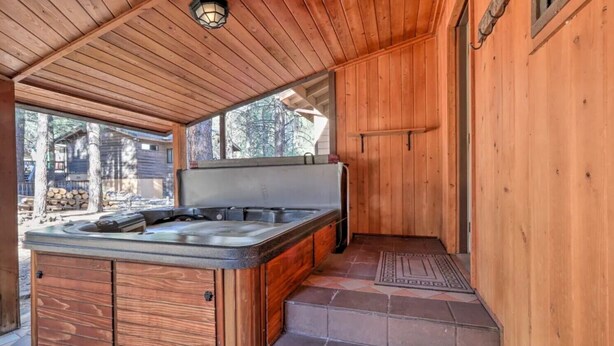 Une cabane en bois dotée d’un bain à remous, d’un petit coin cuisine et offrant une vue sur la forêt environnante.