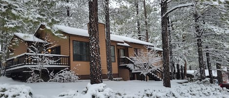 A two-story lodge with a wooden exterior, a balcony, and snow-covered surroundings.