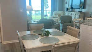 Un comedor con una mesa dispuesta para cuatro personas, rodeada de sillas. Un televisor está montado en la pared sobre la mesa.