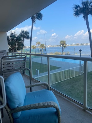 Enjoy unobstructed views of the lake or sea from this balcony, featuring a wicker chair and glass barrier.