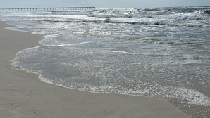 Una playa con un muelle que se adentra en el océano.