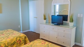 Une chambre avec deux lits, une commode, un téléviseur et deux plantes en pot.