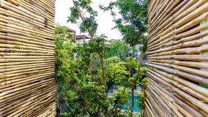 A view through a bamboo fence with lush green trees and a pool in the background. - Eco-sustainable Luxury Between Beach Hotspots & Tulum Town by Stella Rentals (Tulum)