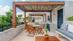 An outdoor patio with a wooden table, chairs, and a potted plant. - Eco-sustainable Luxury Between Beach Hotspots & Tulum Town by Stella Rentals (Tulum)