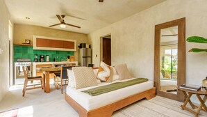 A modern bedroom with a wooden bed, a dining area with a green-tiled backsplash, and a kitchen with a stove and refrigerator. - Eco-sustainable Luxury Between Beach Hotspots & Tulum Town by Stella Rentals (Tulum)