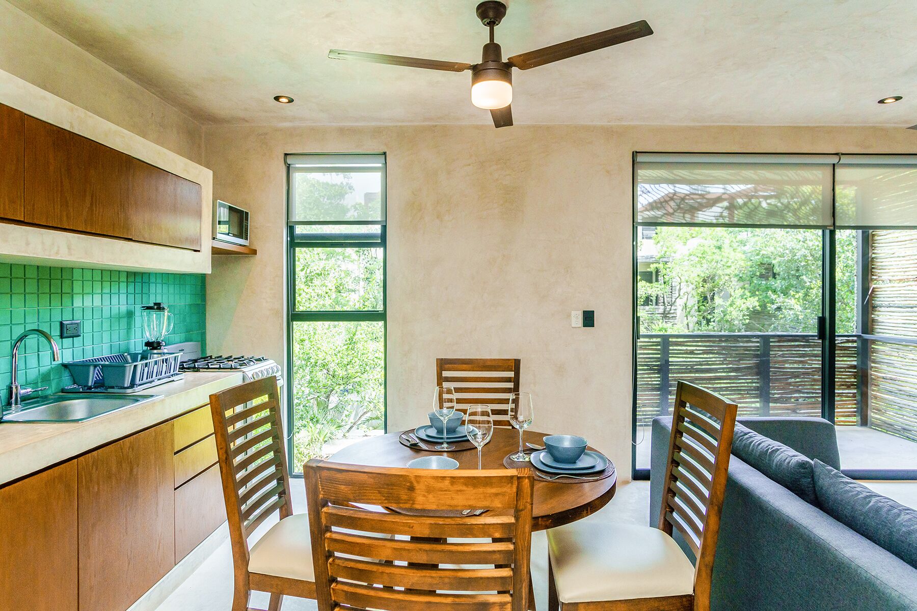 A modern kitchen with wooden cabinets, a dining table set for four, and a ceiling fan.