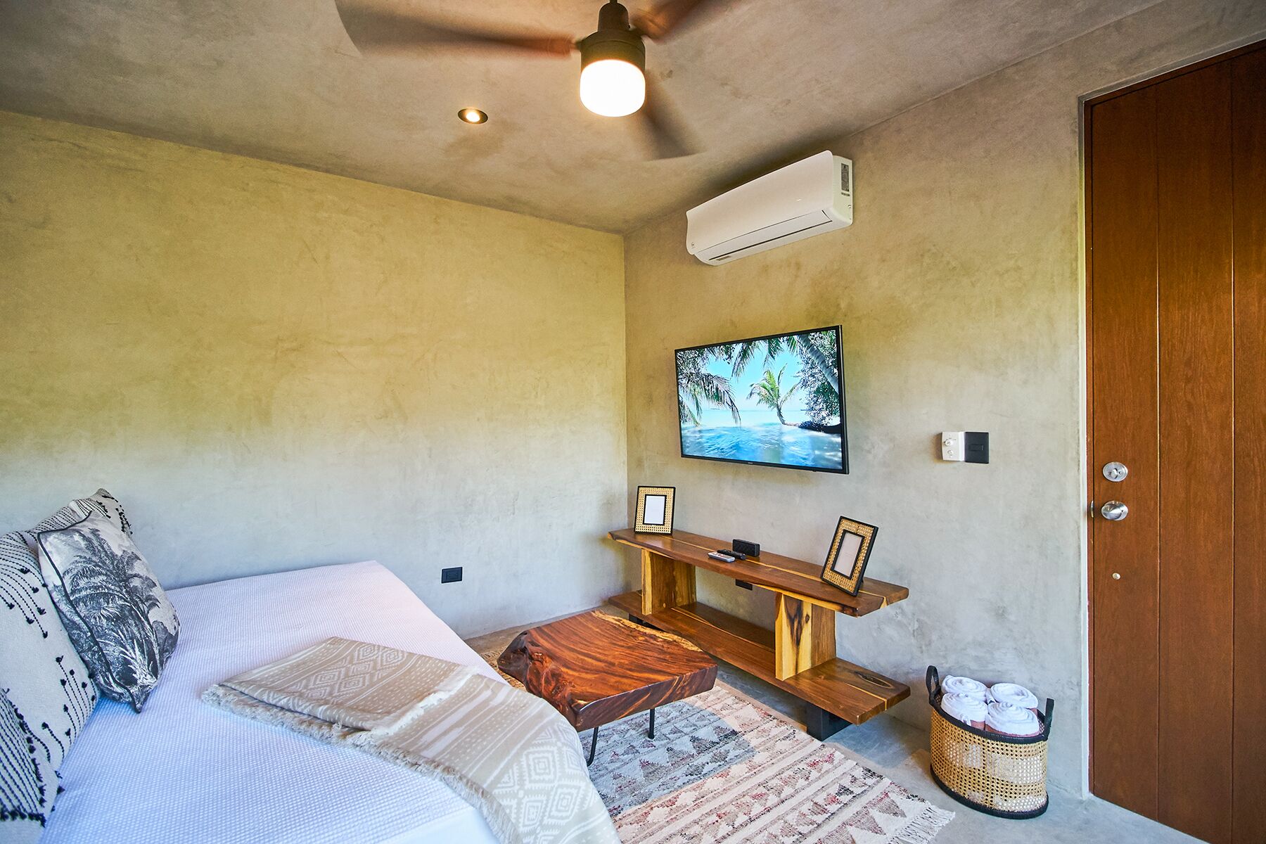 A bedroom with a bed, a desk, a TV, and an air conditioner.