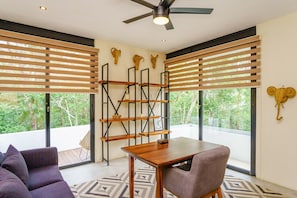 Una sala de estar moderna con una mesa de comedor de madera, un sofá y un ventilador de techo.