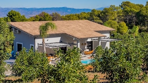 Una casa moderna con techo de tejas, piscina y exuberante follaje.