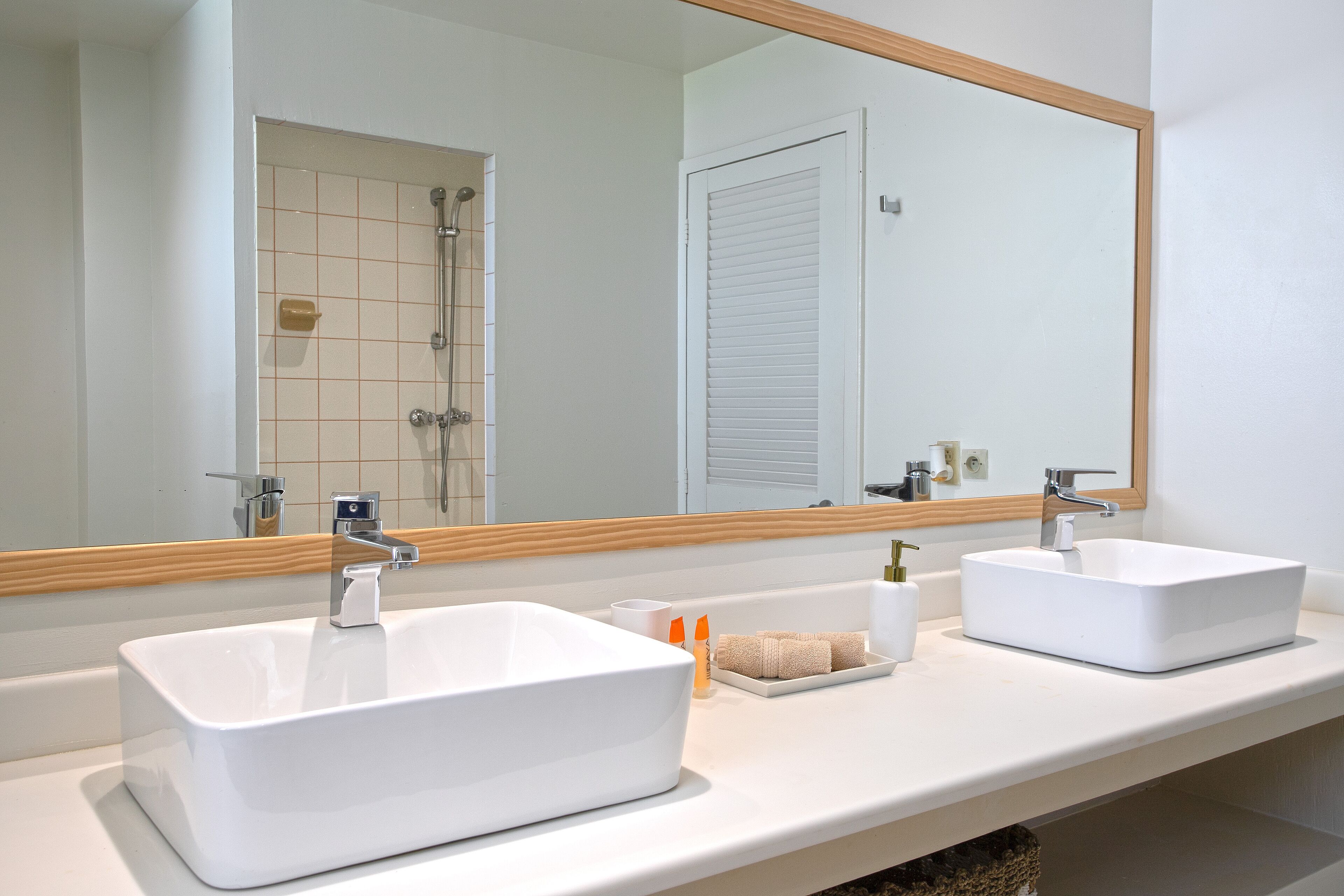 Ein Badezimmer mit zwei weißen Waschbecken, einem Spiegel und einer Dusche.