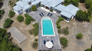 Vista aérea de una casa moderna con piscina, una terraza con sillones de descanso y un patio cubierto.