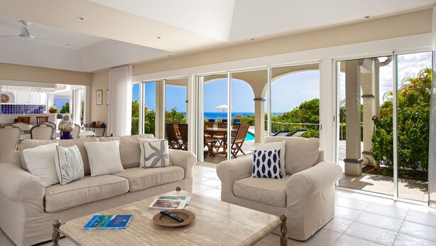 Un amplio salón con un gran ventanal con vistas a una piscina y jardín.