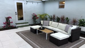 A patio with a white sofa set, a wooden coffee table, and a patterned rug. - Stylish - Minutes From Beach, Bars & Eateries (West Palm Beach)