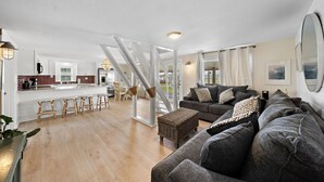 Een ruime woonkamer met een grote bank, een eettafel en een keuken op de achtergrond.