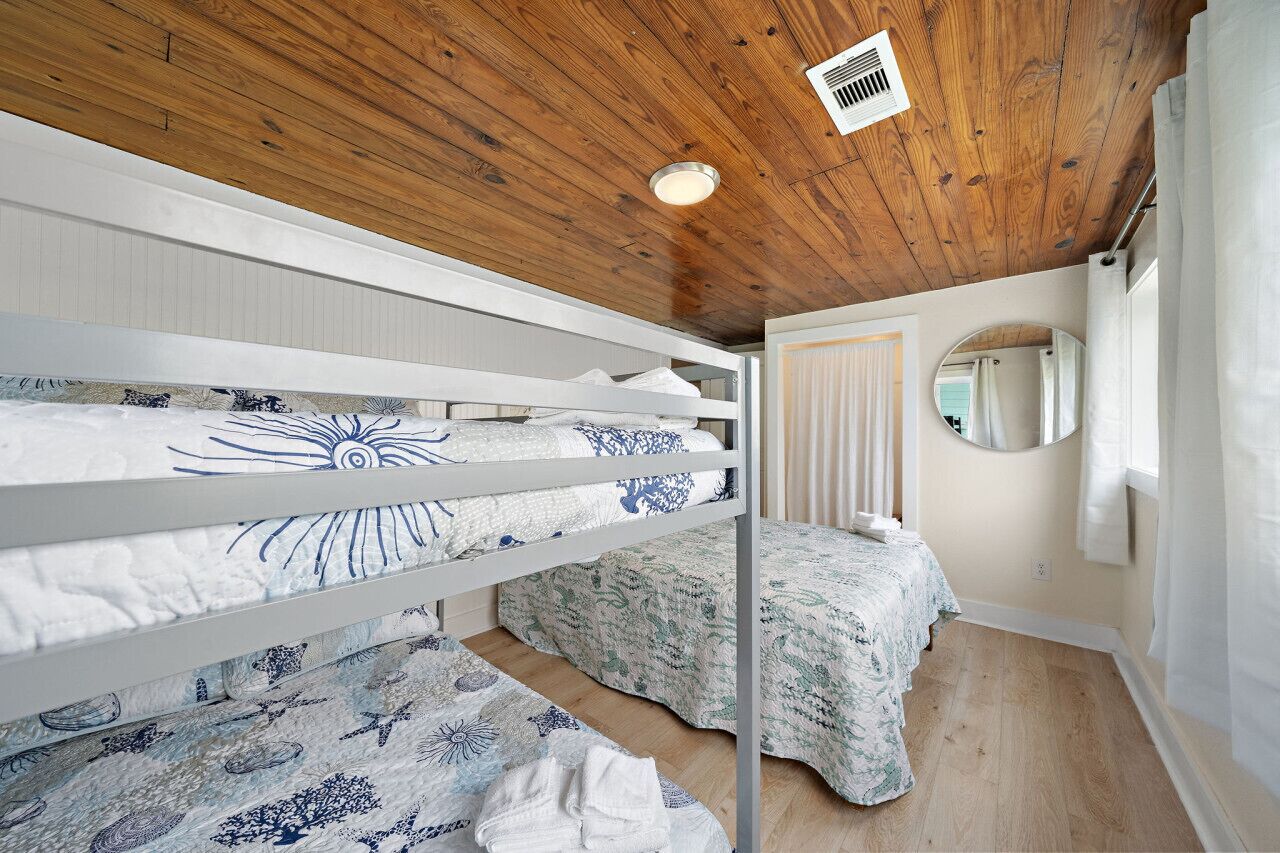 A bedroom with bunk beds, a round mirror, and a wooden ceiling.