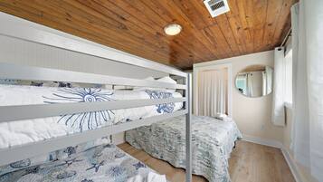 A bedroom with bunk beds, a round mirror, and a wooden ceiling.