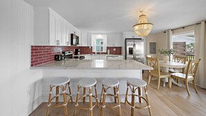 Een moderne keuken met witte kasten, een marmeren eiland en een kroonluchter.