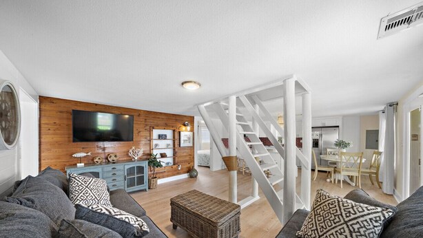 Een moderne woonkamer met een trap, grijze banken, een televisie en een houten wand.