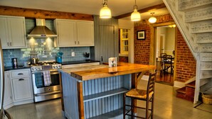 A kitchen with a central island, wooden cabinets, a stove, and hanging pendant lights.