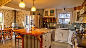 A kitchen with a central island, wooden cabinets, a stainless steel refrigerator, and a stove.
