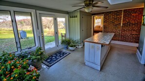 A kitchen with a brick wall, a ceiling fan, and a view of the outdoors.