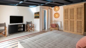 Ein modernes Schlafzimmer mit einem großen Bett, einem Fernseher, einem Kleiderschrank und einem Sessel.