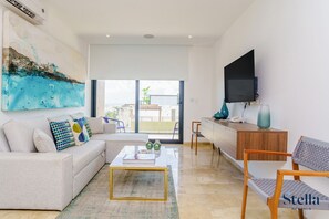 Un salon moderne avec un canapé, une table basse et un téléviseur à écran plat.