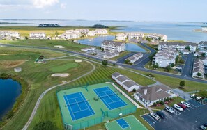 Luchtbeeld van een woongebied met meerdere appartementencomplexen, een tennisbaan en een waterpartij.