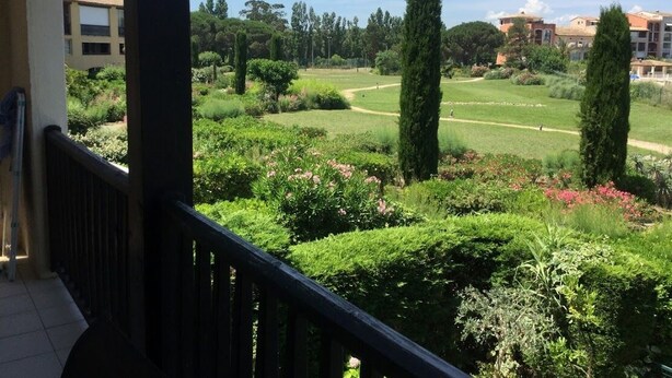 Ein Balkon mit Blick auf einen gepflegten Garten, darunter ordentlich geschnittene Hecken und verschiedene Pflanzen.