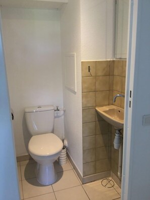 A small, compact bathroom with a toilet, sink, and a tiled shower area. - Les Marines de Gassin à 200 m de la Plage (GASSIN)