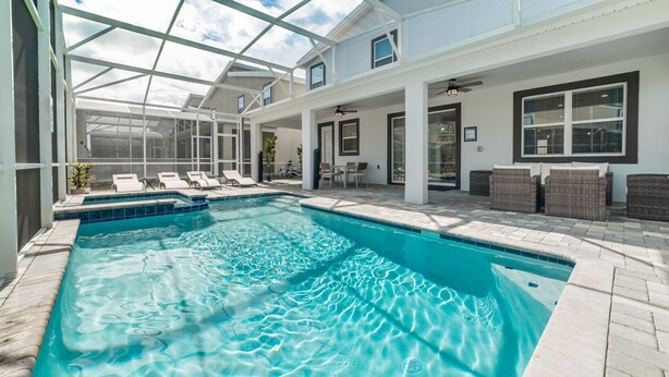 A swimming pool with a glass ceiling, lounge chairs, and wicker furniture. - 5 Star Villa Zenith – The Summit of Opulent Living (Orlando)