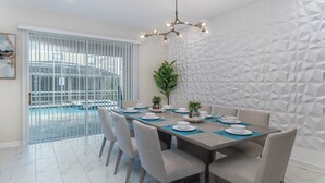 A dining area with a pool view, a geometric wall, and a modern chandelier. - 5 Star Villa Zenith – The Summit of Opulent Living (Orlando)