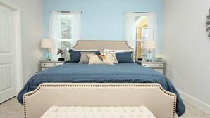 Een slaapkamer met een bed, twee nachtkastjes, een lamp en een raam met gordijnen.