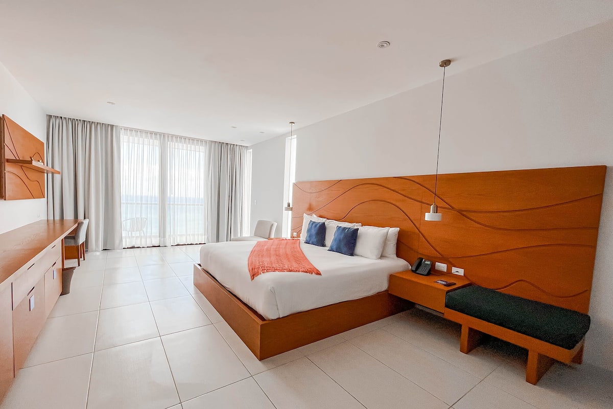 Quarto de hotel moderno com uma cama grande, uma escrivaninha e um banco.