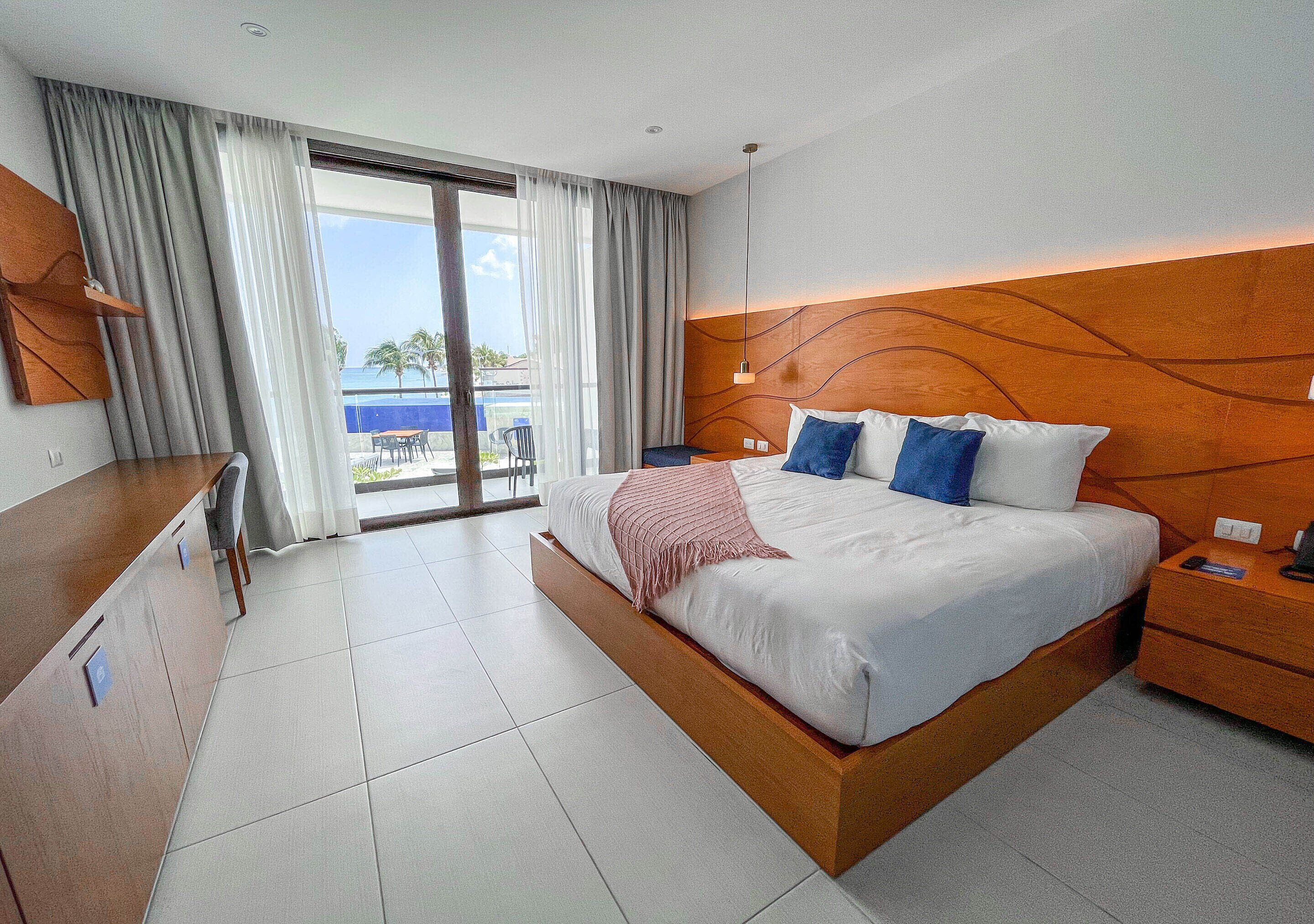 Una habitación de hotel moderna con una cama grande, un escritorio y vista al océano.