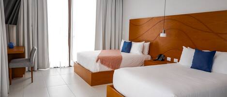 A hotel room with two beds, a TV, and a desk with a chair.