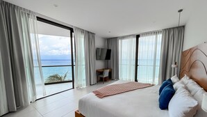 A modern bedroom with a large bed, a desk, and a TV.