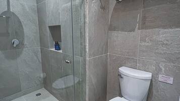 A modern bathroom with a glass-enclosed shower, a white toilet, and a towel rack.